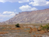 Slopes of Mancos shale capped by Mesaverde sandstone make up the Book Cliffs, here along I-70 northeast of Grand Junction